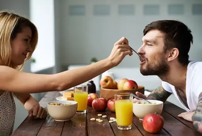 a woman feeds a man nuts to increase activity